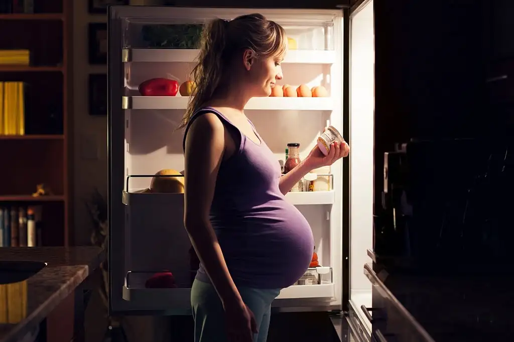 lady craving food during pregnancy at refrigerator