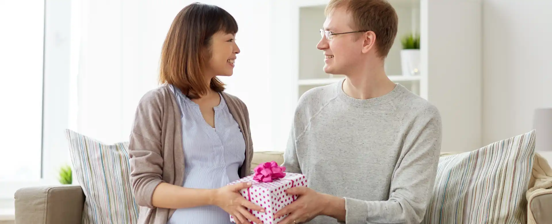 pregnant wife giving husband gift to convince him to find baby gender early