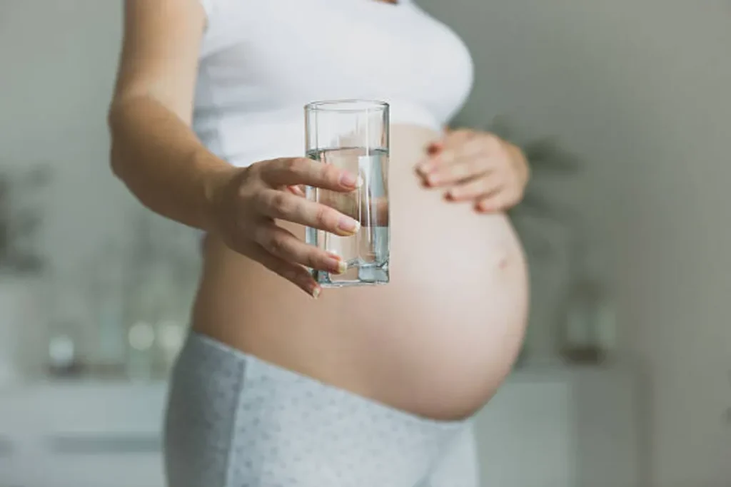 pregnant woman holding glass of water hydration concept